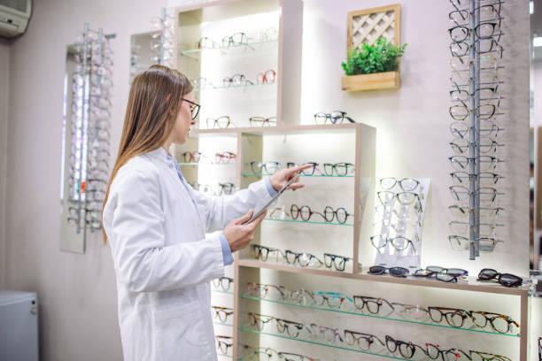 istock Optician pointing to eyeglasses on modern display rack 2164774359