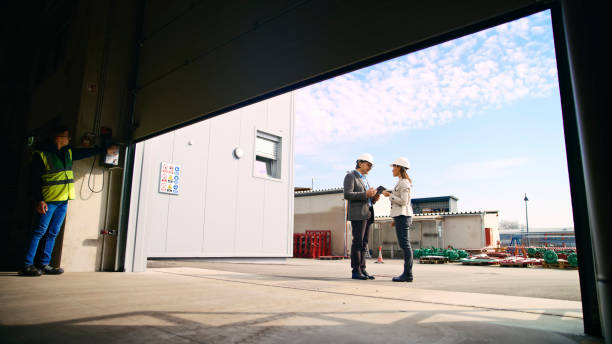 istock Partners Discussing Outside Warehouse while Engineer Standing by Entrance 2164777323