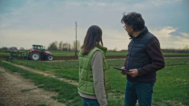 istock Agronomists Looking at Tractor and Discussing at Organic Farm 2164777986