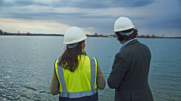 istock Female Engineer Planning Water Conservation with Architect at Reservoir 2164778547