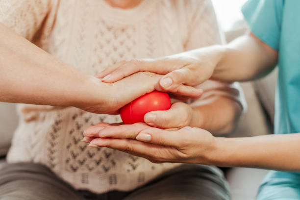 istock Nurse assisting elderly patient with hand physical therapy using red stress ball closeup, selective focus 2164778676