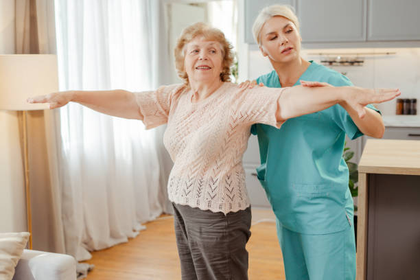 istock Nurse assisting elderly woman doing physical therapy exercises at home 2164778774