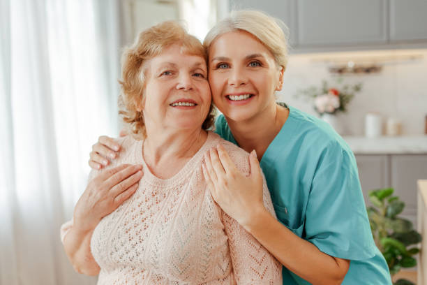 istock Nurse hugging elderly woman at home looking at camera 2164778779