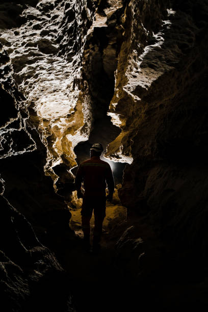 istock Speleologist descend by the rope in the deep vertical cave tunnel. Karst cave 2164780080