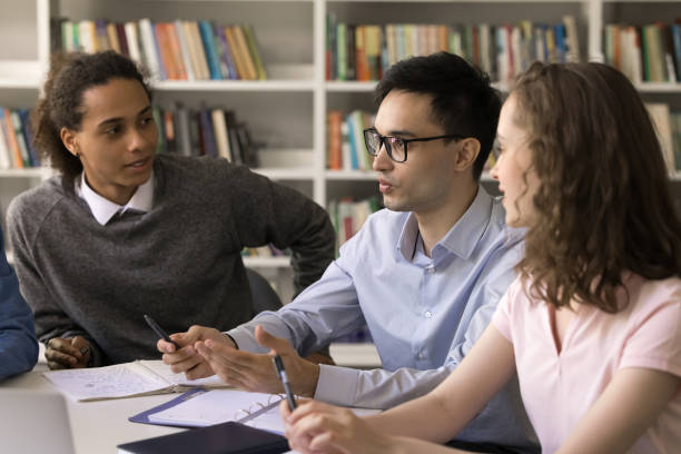 istock Serious Indian guy talk to schoolmates met in library 2164780707