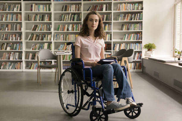 istock Student girl with mobility impairment posing for camera in library 2164781772