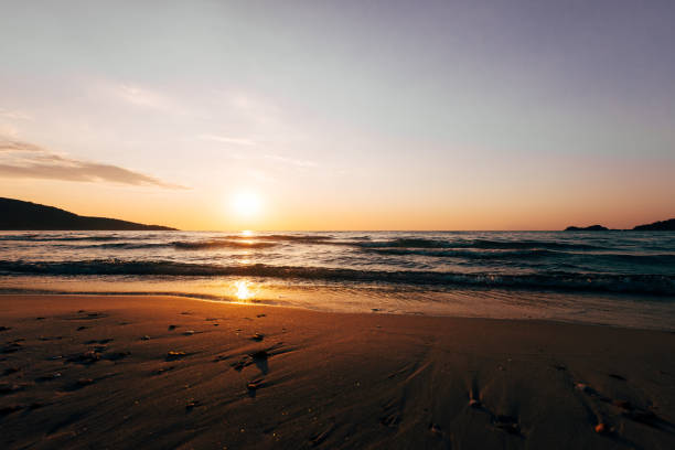 Gentle waves rolling onto the shore reflecting the warm glow of the setting sun