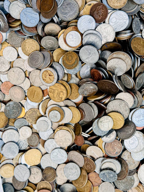 A diverse collection of coins from various countries, featuring different denominations and designs. The coins are piled together, indicating a mix of currencies and historical periods.