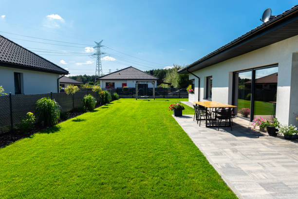 Beautiful garden with green grass, visible terrace table and house in beautiful summer weather, very wide shot. stock photo