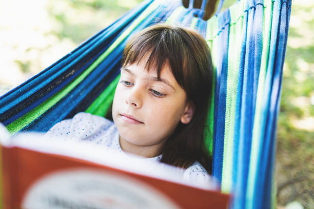 istock Little girl reading interesting book in hammock 2164792634
