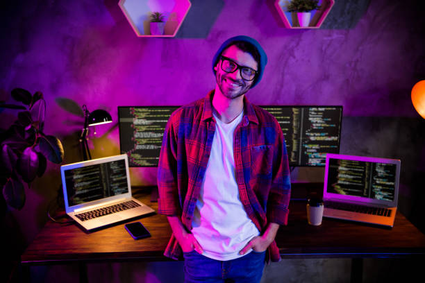 istock Photo of smiling positive coder dressed hat eyewear working late evening shift indoors workplace workstation loft 2164794584