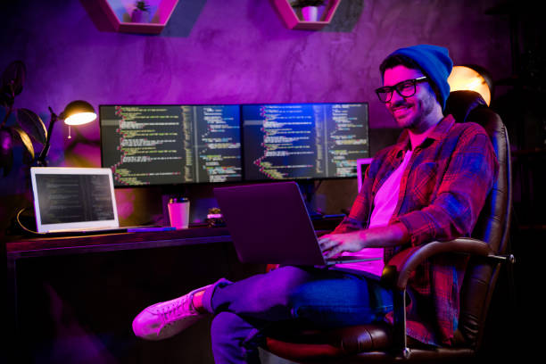 istock Photo of positive happy coder dressed hat eyewear typing modern device indoors workplace workstation loft 2164794586