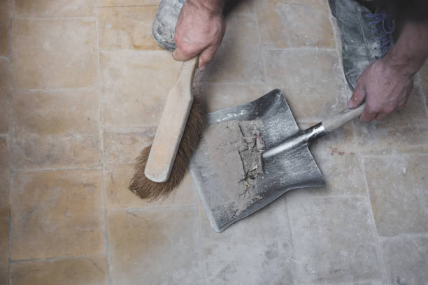 Caucasian male builder sweeps construction debris.