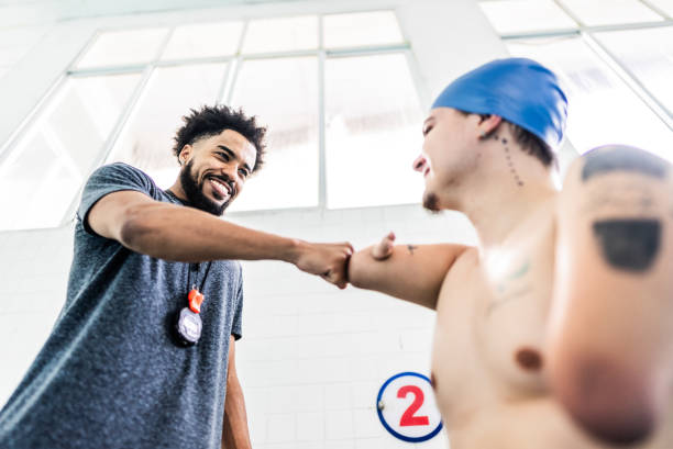 Competitive para athlete swimmer with double arm and leg amputations greeting instructor at swimming pool