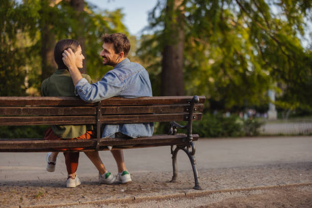 Happy young couple in love sitting on a park bench