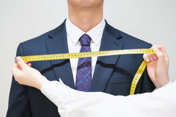 istock The tailor measures the suit with a measuring tape close-up, front view. 2164810894