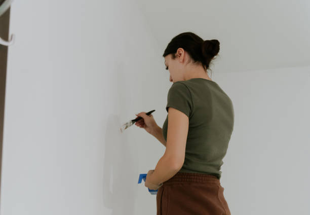 istock A young girl paints the walls with a brush using white paint. 2164811407