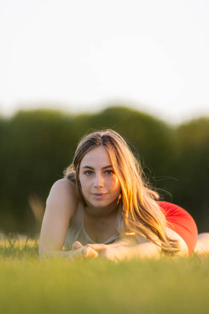 Portrait of a young blond woman lying on the grass field. Scan of a negative.