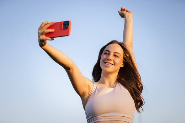istock Pretty young lady is taking selfie at public park at sunset. 2164812337