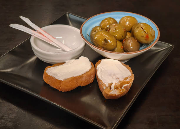 Close-up shot of Italian appetizer green olive and bruschetta with cream cheese. concept : Mediterranean snacks, Italian appetizers & tapas.