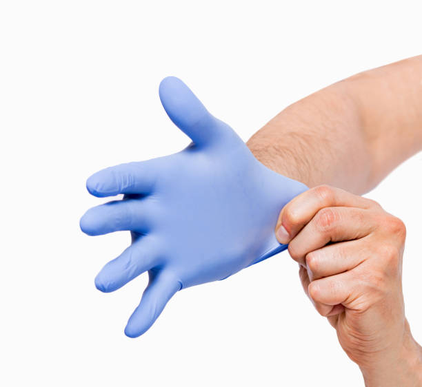man putting blue latex gloves man hands putting on a blue latex gloves isolated on a white background putting on latex gloves stock pictures, royalty-free photos & images
