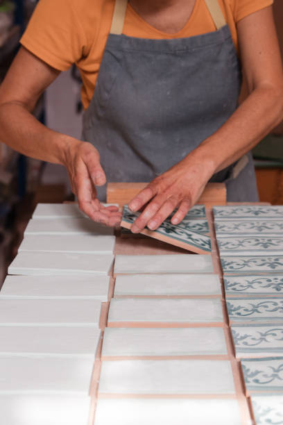 Female artist working in her ceramics studio aligning tiles by hand