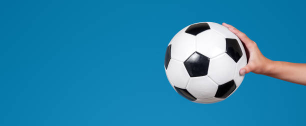 istock Panoramic image of hand holding soccer ball. Space for text. Isolated on blue background. 2164823431