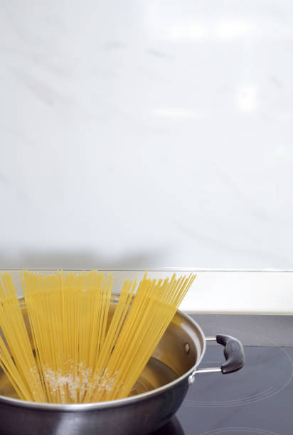 istock Boiling Spaghetti with salt on a pot on stove in white marble kitchen background 2164825651