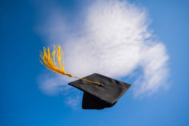istock Graduation cap flies against the blue sky. 2164826622