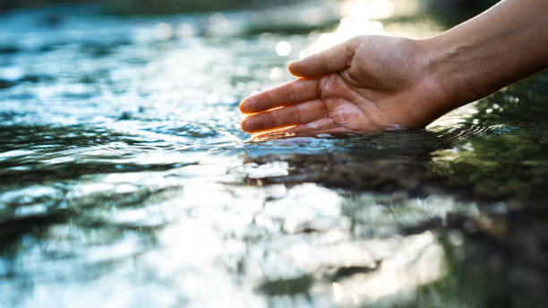 istock A female hand touching the river water 2164826925