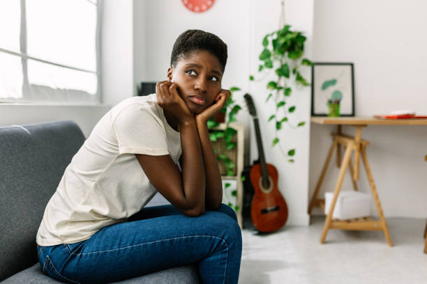 istock Worried young african woman sitting alone on sofa thinking about problems 2164829677