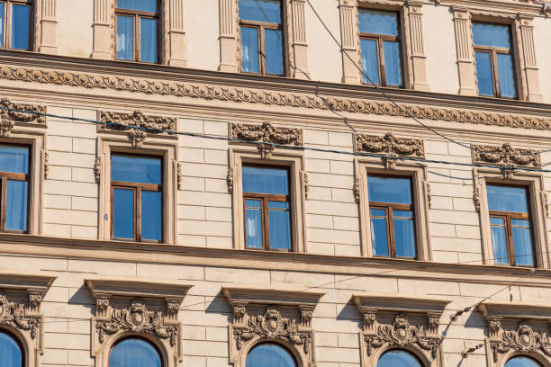 Side view of traditional ornate beige coloured facade with group of windows on wall of residential building in Saint Petersburg, Russia. Copy space. Architecture and city street background theme.
