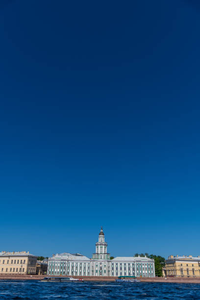 Russia, Saint Petersburg - July 09, 2024: Side view of Kunstkamera green building across Neva river in a sunny summer day. Clear blue sky. Copy space. Russian culture and architecture theme.
