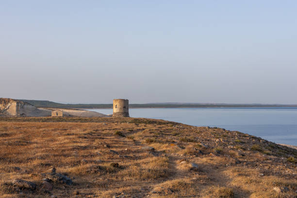Historic stone coastal tower under a clear blue sky in Torre del Pozzo, Sardinia.