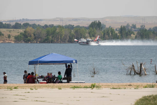 Flying on the surface of the water past beach goers at Chatfield State Park, a fire fighting CL-415 scooper tanker vacuums up to 1600 gallons of water for extinguishing flames on the Quarry Fire in Deer Creek Canyon, Littleton, Colorado on July 31, 2024.