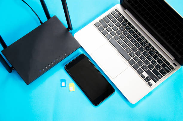 istock WiFi router, SIM card, smartphone, laptop computer placed on blue background. Communication equipment 2164836018