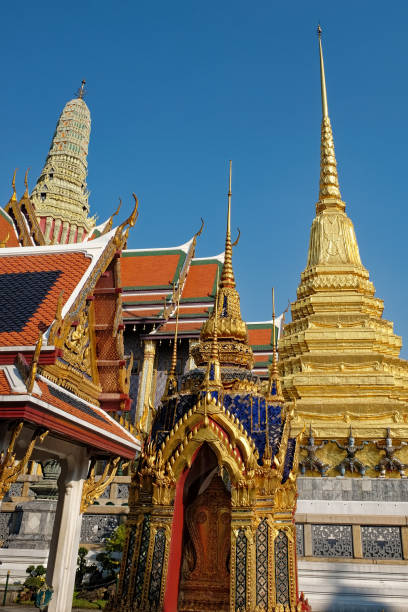 istock A picturesque low-angle view offers a glimpse of a Thai temple's distinctive red roofs, intricate gold accents, and a towering white spire standing tall beneath a serene blue sky. 2164839095
