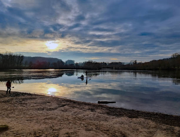 Beautiful idylic scene - sunset over the lake. Clouds lit by the setting sun are mirrored on the water surface. Around the lake trees grow.