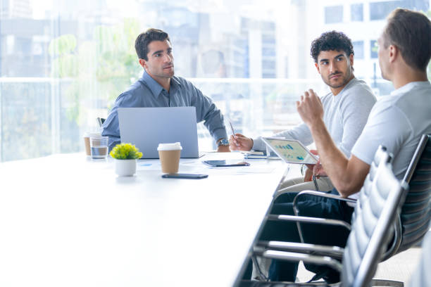 istock Three business men meeting and sharing ideas in the board room. They are using computers and digital tablets 2164863353