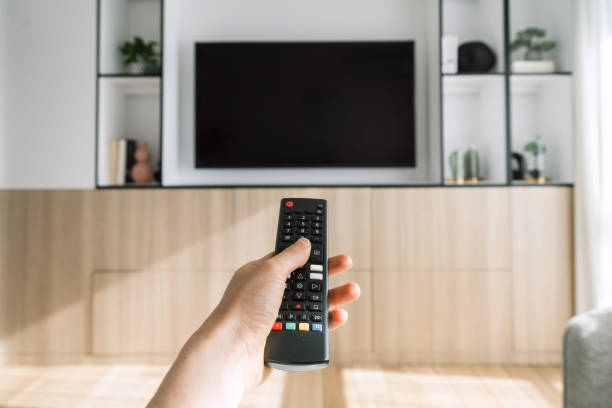 istock Hand holding remote control in front of copy space tv display 2164864120