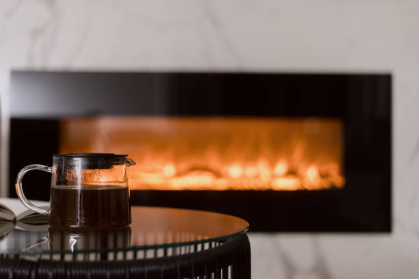Glass teapot with herbal tea on side table against fireplace