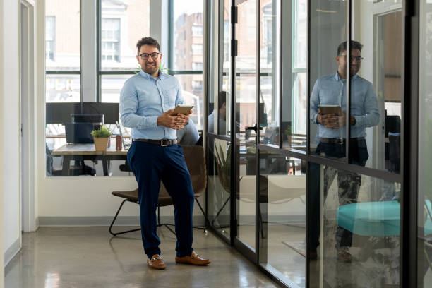 istock Mexican man working in a modern office holding an Ipad 2164866260
