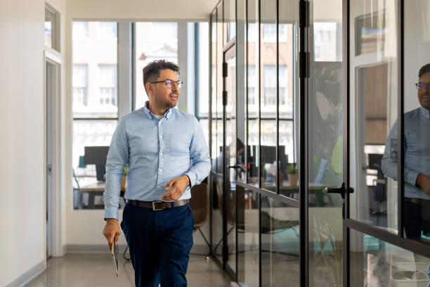 istock Mexican man working in a modern office holding an Ipad 2164866272