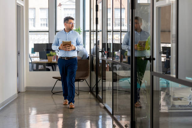 istock Mexican man working in a modern office holding an Ipad 2164866273