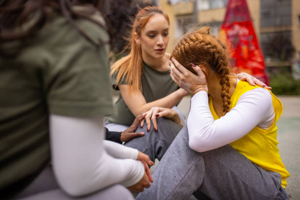Multiracial group of women, young female player got injured during a game outdoors on urban basketball court.