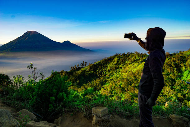 istock Photographer in action at sunrise, perched atop a mountain. 2164875430