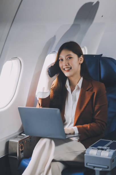 istock Young Asian executive excels in first class, multitasking with digital tablet, laptop and smartphone. Travel in style, work with grace. 2164882518