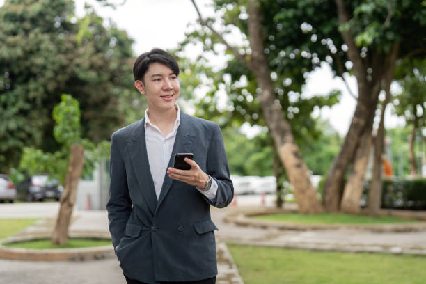 istock Young Professional Man in Business Suit Using Smartphone Outdoors in a Park Setting 2164886322
