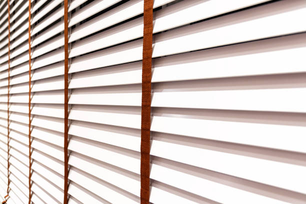 Stylish white wooden blinds on the window. Detailed furniture for modern interior