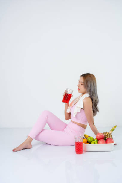 istock Active women often focus on sportswear that supports their workouts without compromising comfort or style. Drinking health drinks and eating fruits, taking photos for a presenter in the studio. 2164890413
